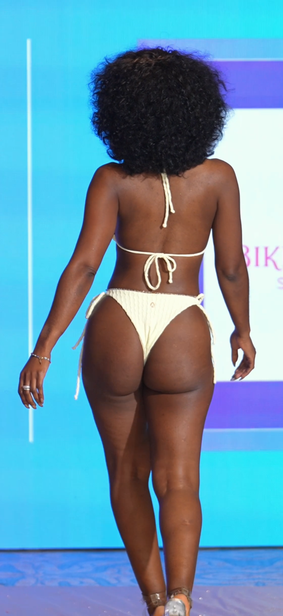Person wearing a beige bikini against a blue background