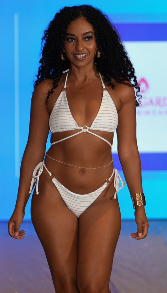 Model wearing a white bikini on a runway with a blue background